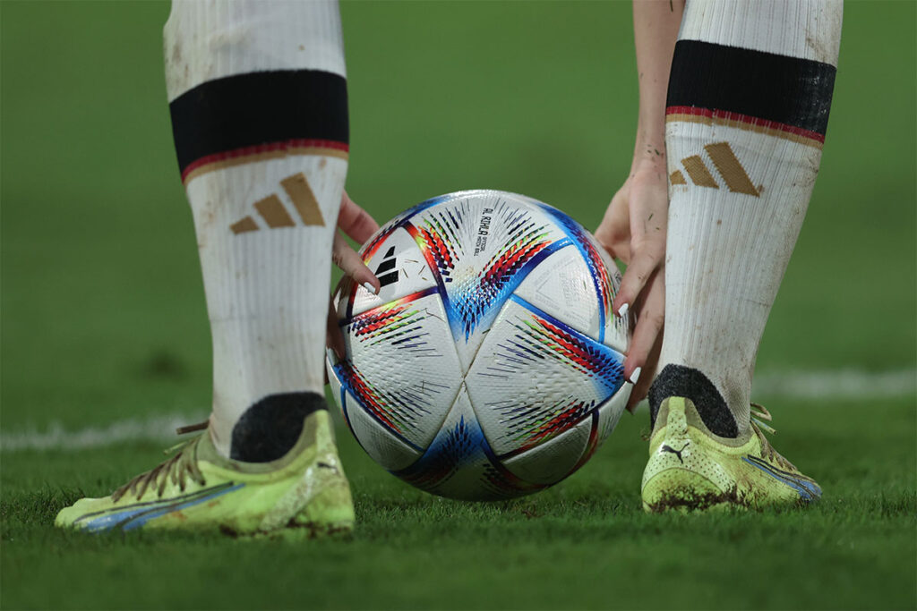 View of a soccer player holding an Adidas soccer ball by their feet