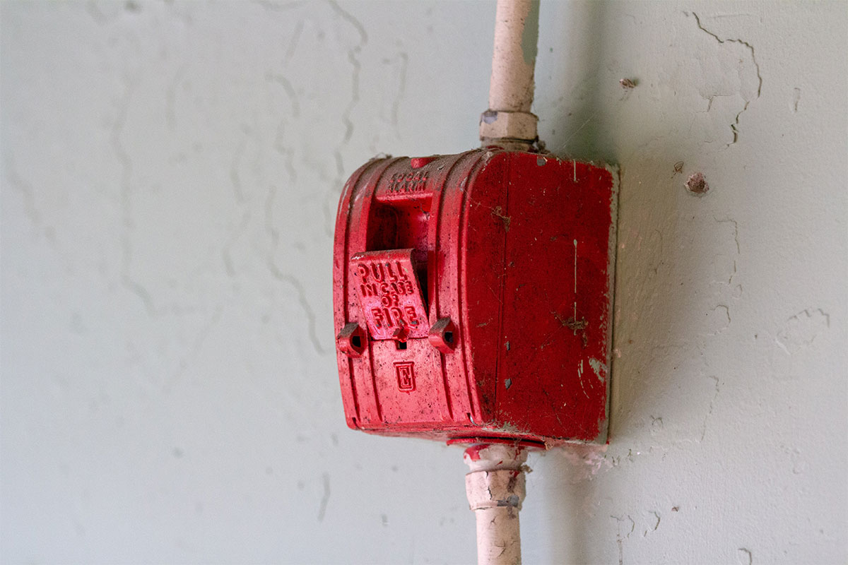 A boxy old red fire alarm on a wall that says "Pull in case of fire" on the front