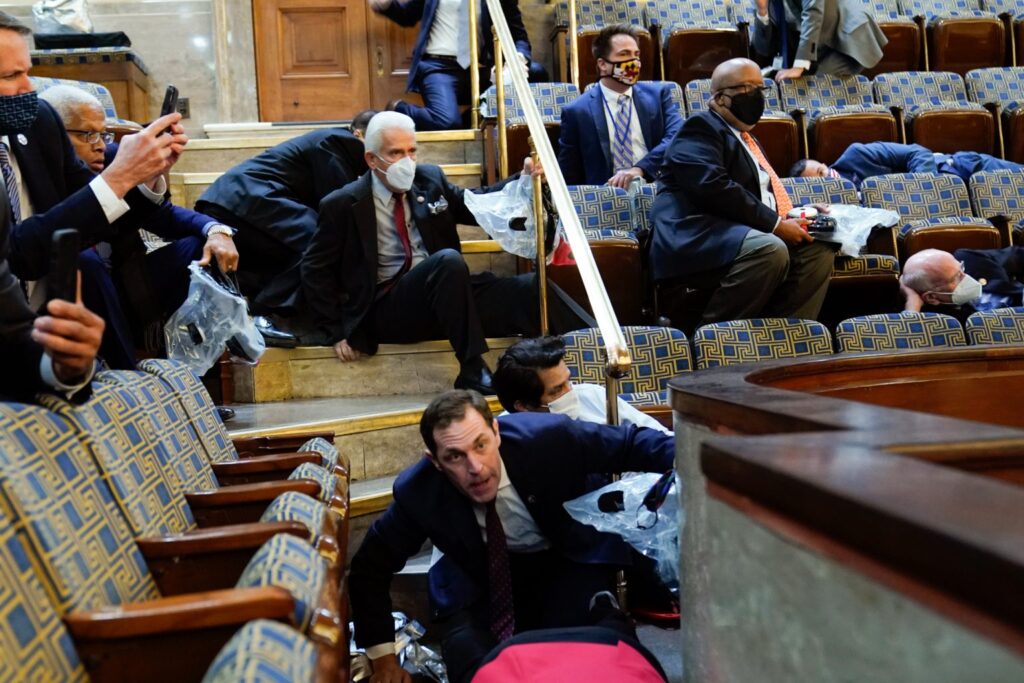 Bennie Thompson sits in the House gallery while other members of Congress lie on the floors of the gallery or hide beneath their chairs during the insurrection