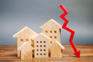 Photo of wooden toy houses with a crashing red arrow pointing into the ground