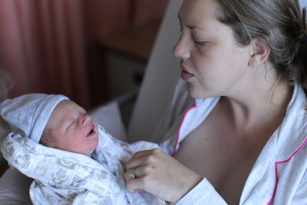 A mother holds her newborn child in a hospital bed