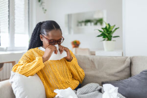 Black woman holding a tissue to her face sneezing