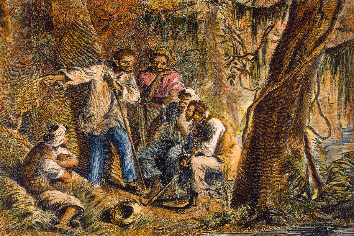 A small group of Black men and women listen to a Black man as they gather in the woods