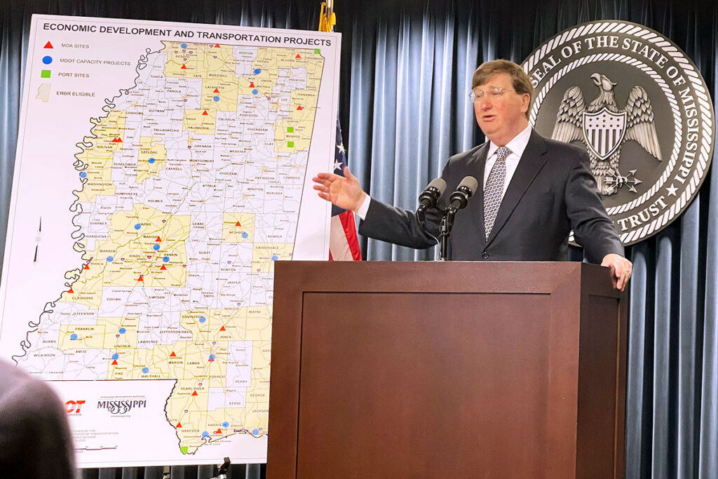 Tate Reeves speaking at a podium and gesturing to a map of Mississippi