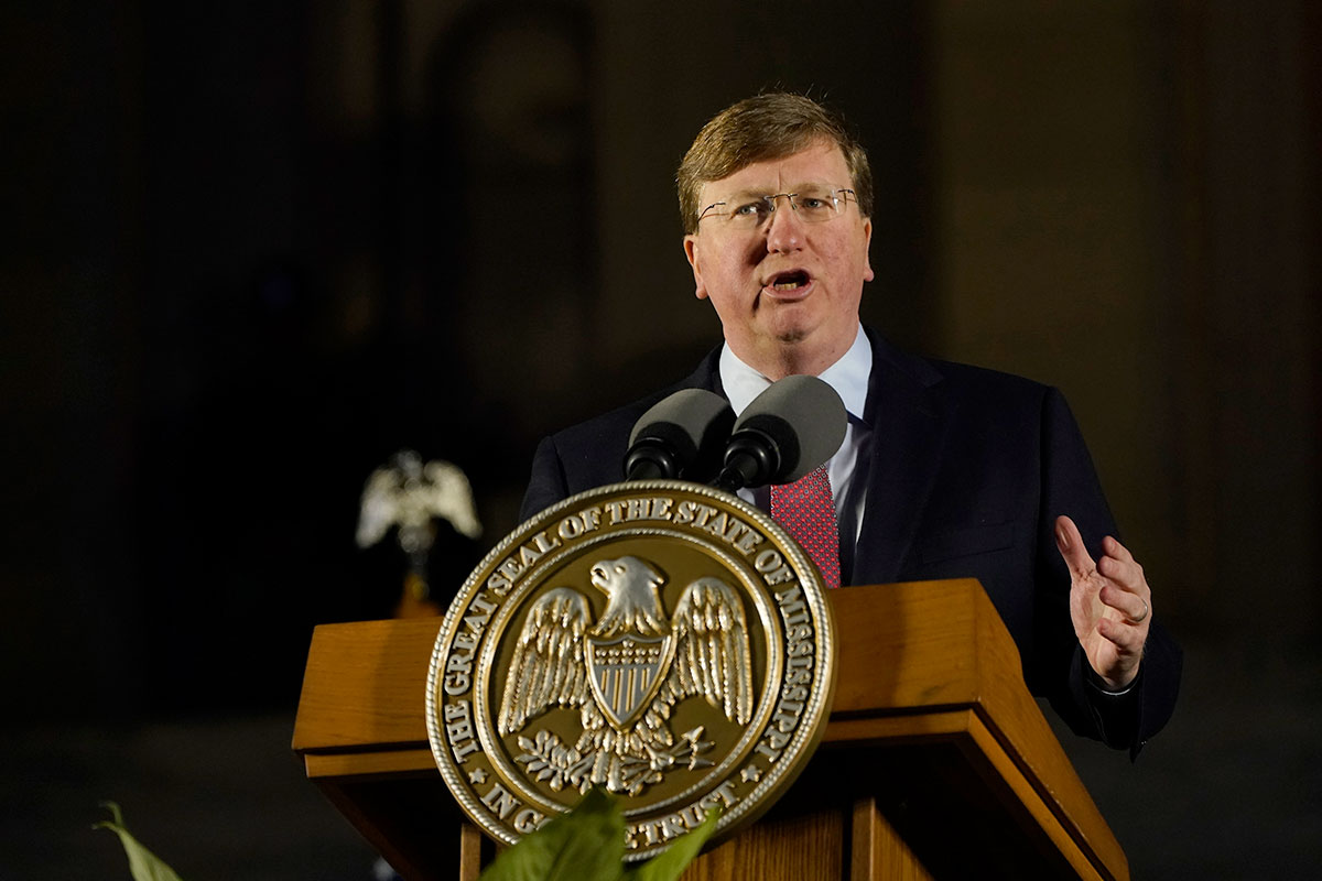 Republican Gov. Tate Reeves speaking at a podium on the steps of the State Capitol of MIssissippi