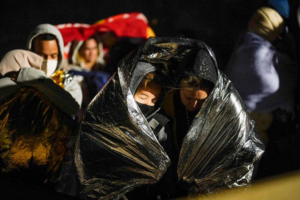 A nighttime shot of people huddled under blankets near the US-Mexico border
