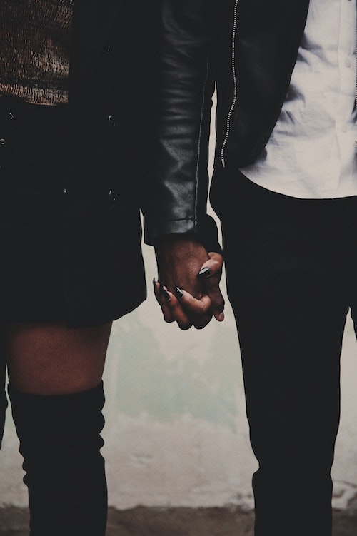 Close up photo of a Black woman and man holding hands