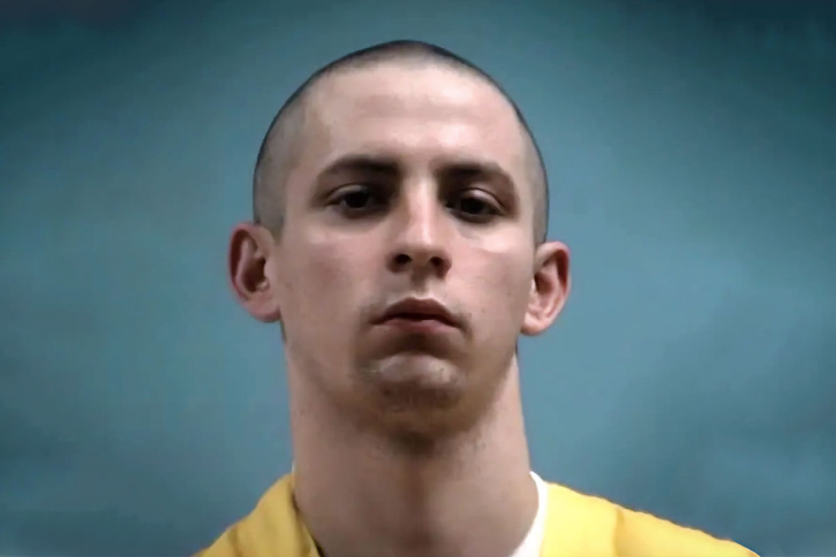 Mugshot of Axel Charles Cox in a yellow jumper against a blue background