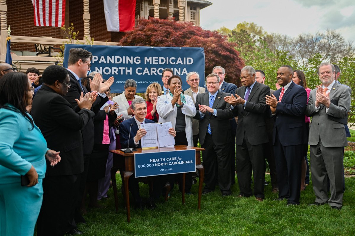 North Carolina Gov. Roy Cooper, a Democrat, signed a bill expanding Medicaid with other officials clapping
