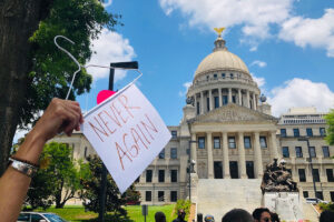 abortion hanger with the sign "Never Again" hanging from the bottom at Mississippi Capitol