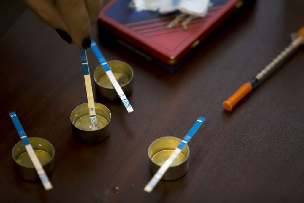 Fentanyl test strips sitting on top of small circular containers