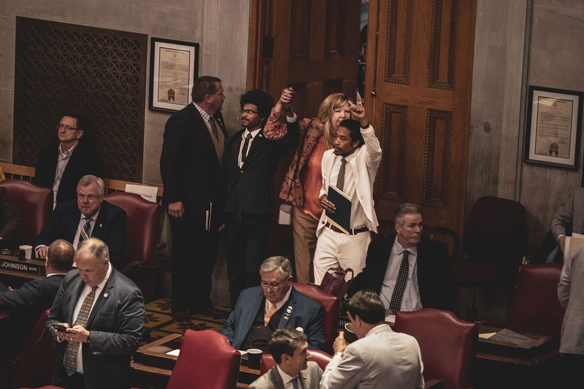 With fists raised, state reps. Justin J. Pearson (left) and Justin Jones (right) walk into the legislative chamber with Rep. Gloria Johnson (gun violence)