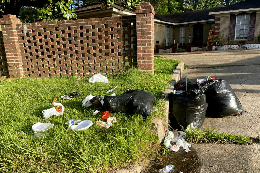 a photo of trash bags with trash strewn outside a home