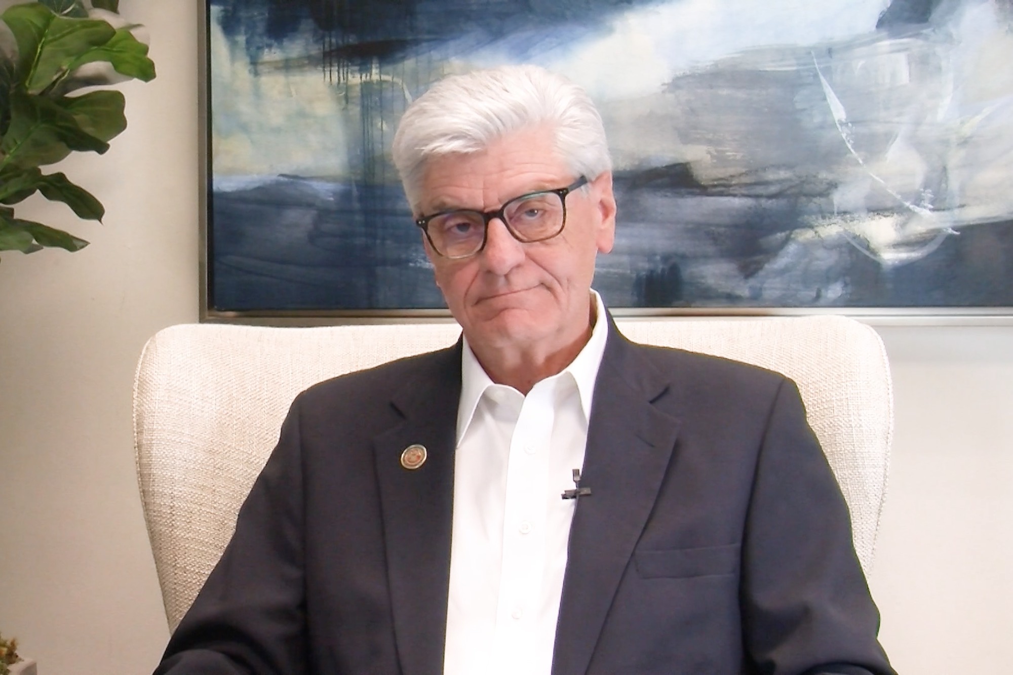 Phil Bryant sitting in a white chair with a stormy painting hanging behind him
