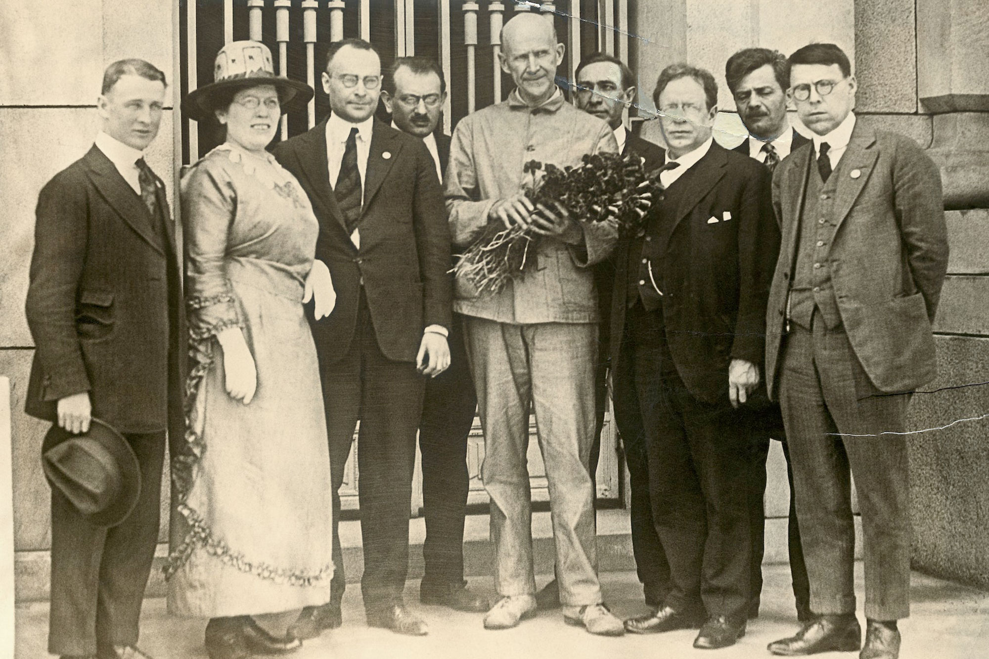 Eugene Debs holds flowers and is flanked by four other people on either side of him