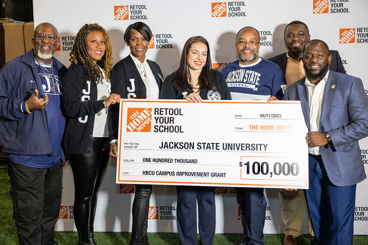 Seven people from Jackson State University hold a check for $100,000