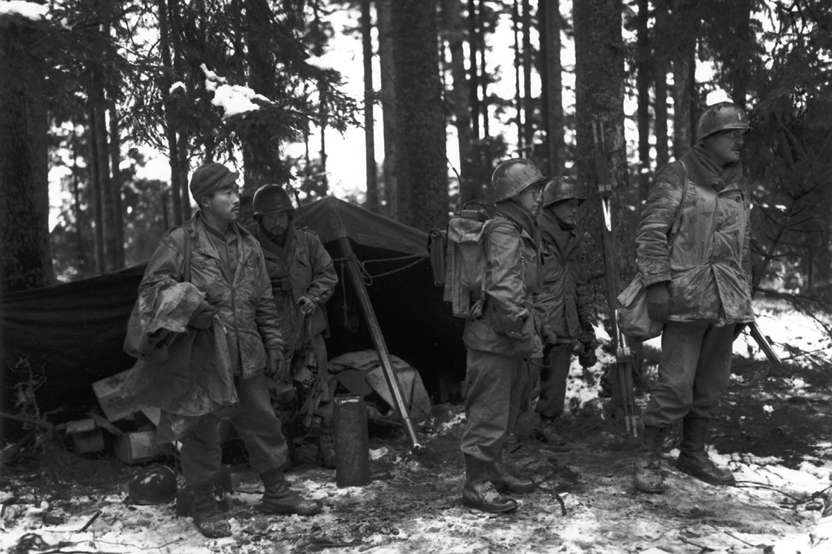 Japanese American soldiers stand in a French forest