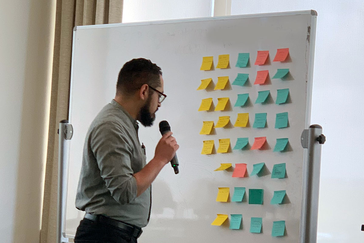 Man standing in front of a white board covered in colorful postit notes