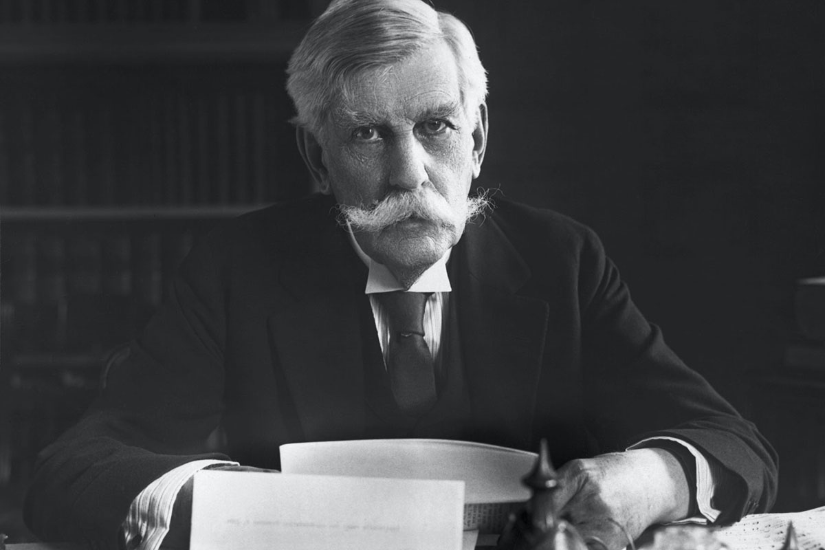 Oliver Wendell Holmes, gray haired and with a big mustache, sitting at a desk. (free speech)