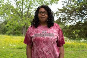 A woman wearing a red Mississippi State tshirt stands outside
