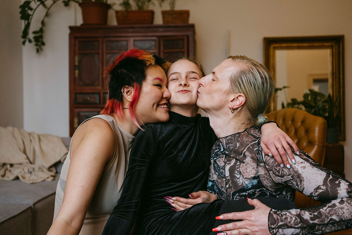 Parents kissing child on either cheek (trans joy)