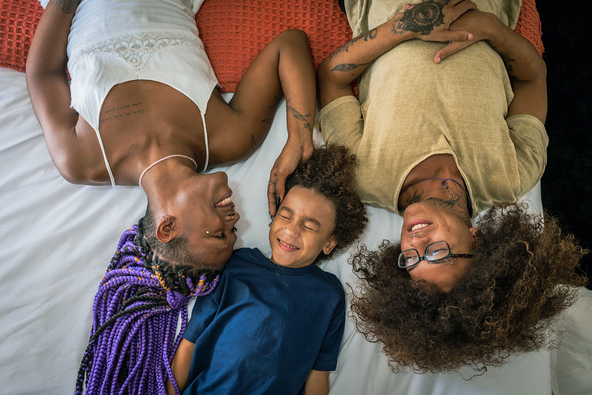Parents and a child lay happily on a bed