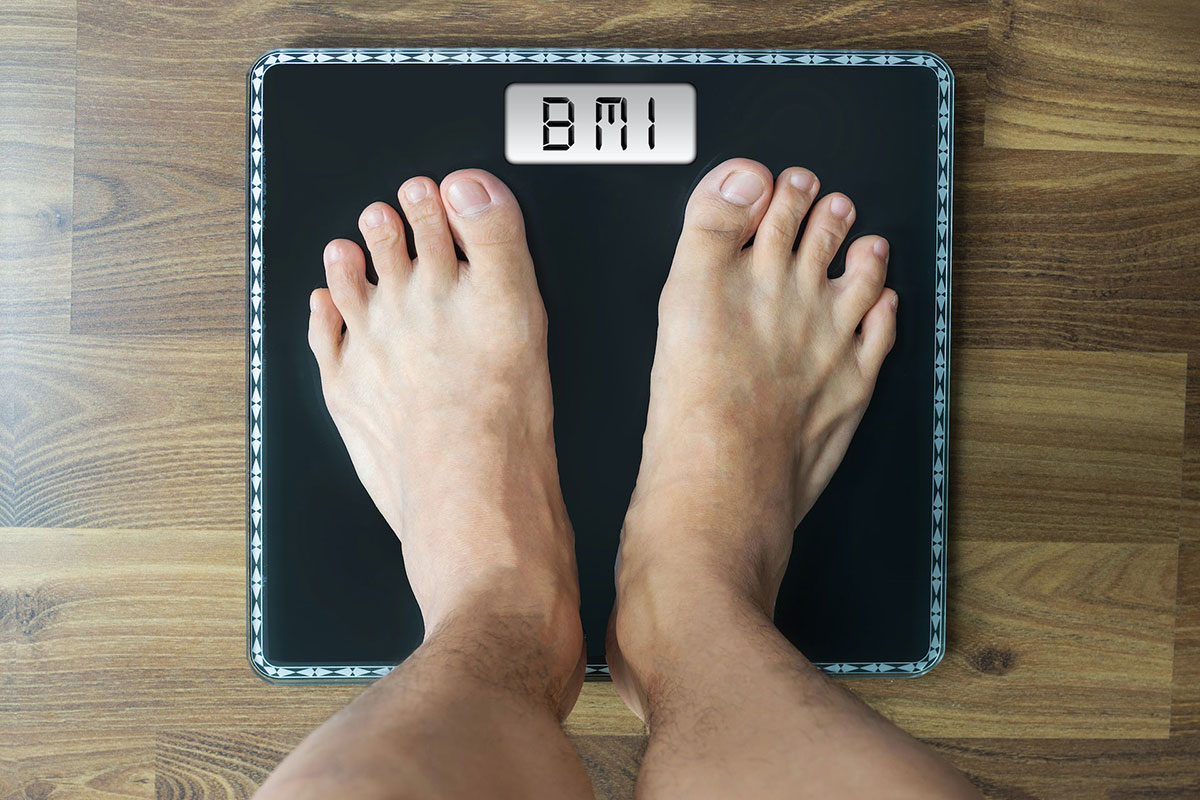Feet standing on a black weight scale with the reading "BMI"
