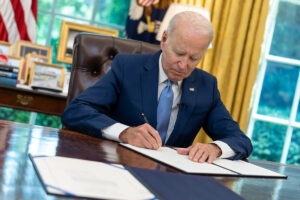 President Joe Biden signs at his desk in the White House