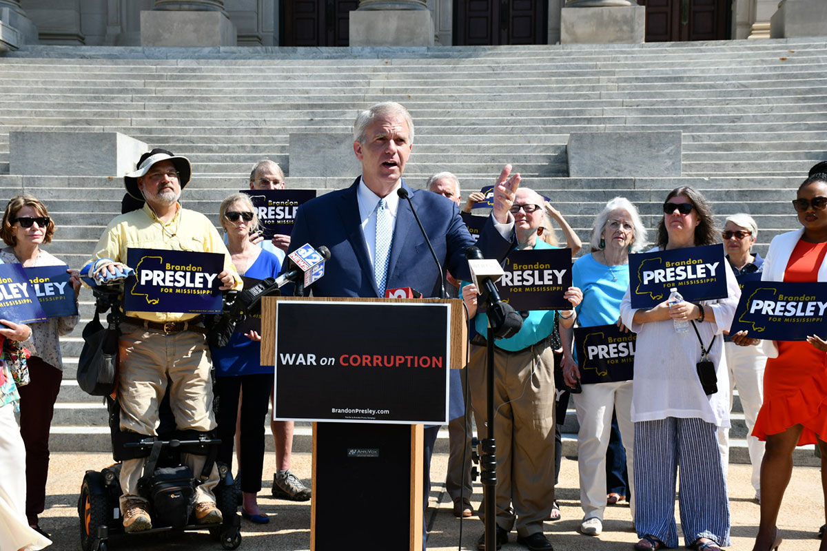 Brandon Presley leading a rally on the War of Corruption in front of stairs while others hold signs with his name