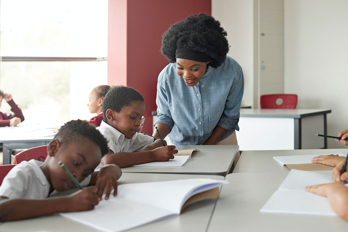 A black women oversees black children doing their schoolwork