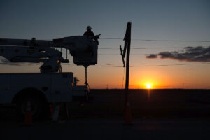 A power truck working on power lines at sunset