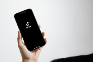 A hand holding a cell phone with TikTok's logo on the screen