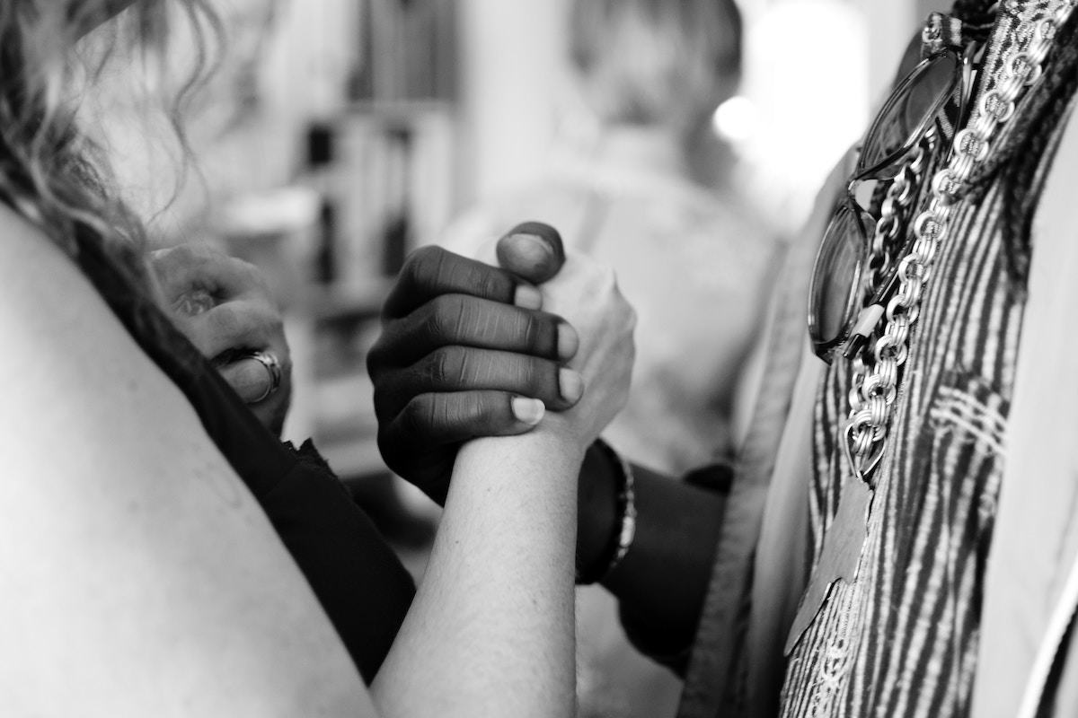 a close-up angle of a white woman and Black man clasping hands (conflict)