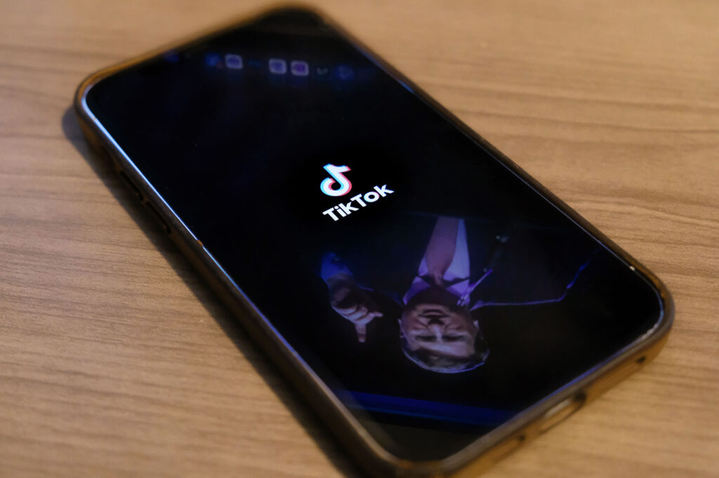 A phone with the tiktok logo on the home screen, and a reflection of Tate Reeves on the bottom