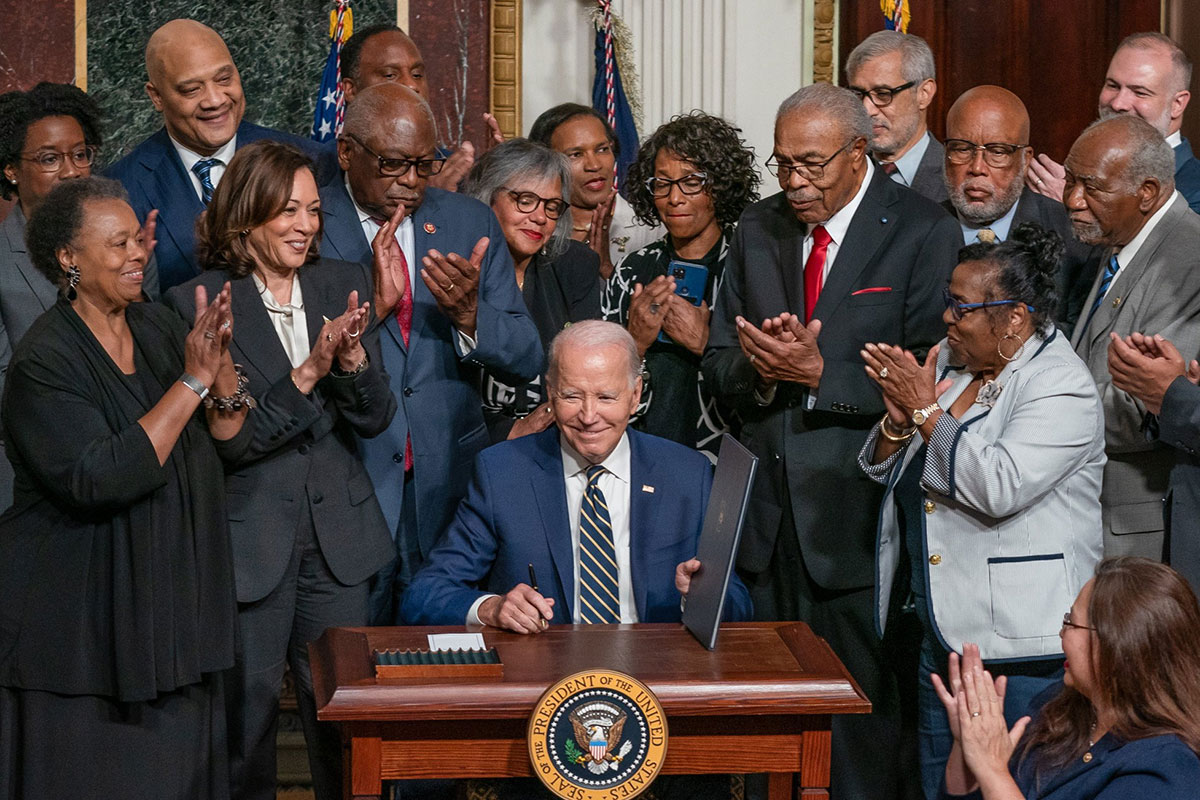 President Biden shown surrounded by clapping officials after the signing of a proclamation regarding Emmett Till and Mamie Till-Mobley