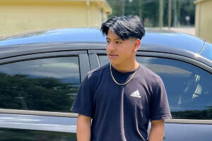 Duvan Tomas Perez stands outside in front of a black car
