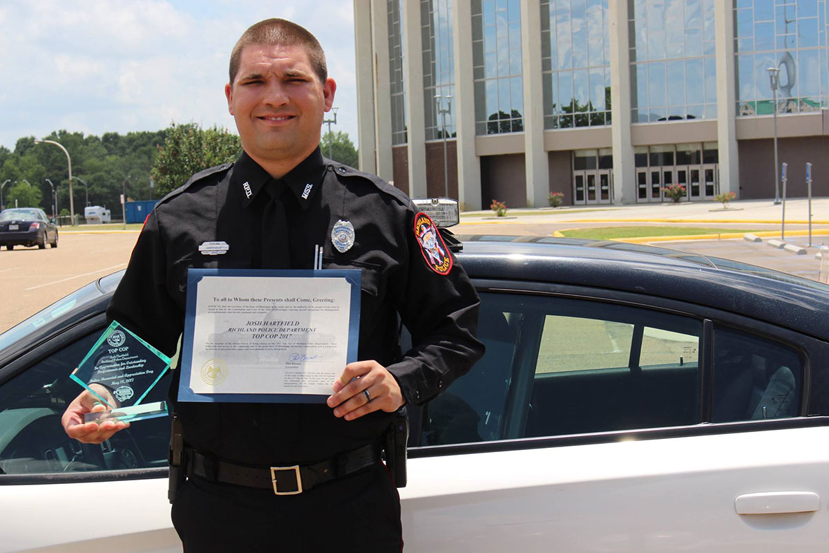 Officer Joshua Hartfield seen sanding outside holding awards