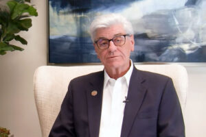 Phil Bryant sitting in a white chair with a stormy painting hanging behind him