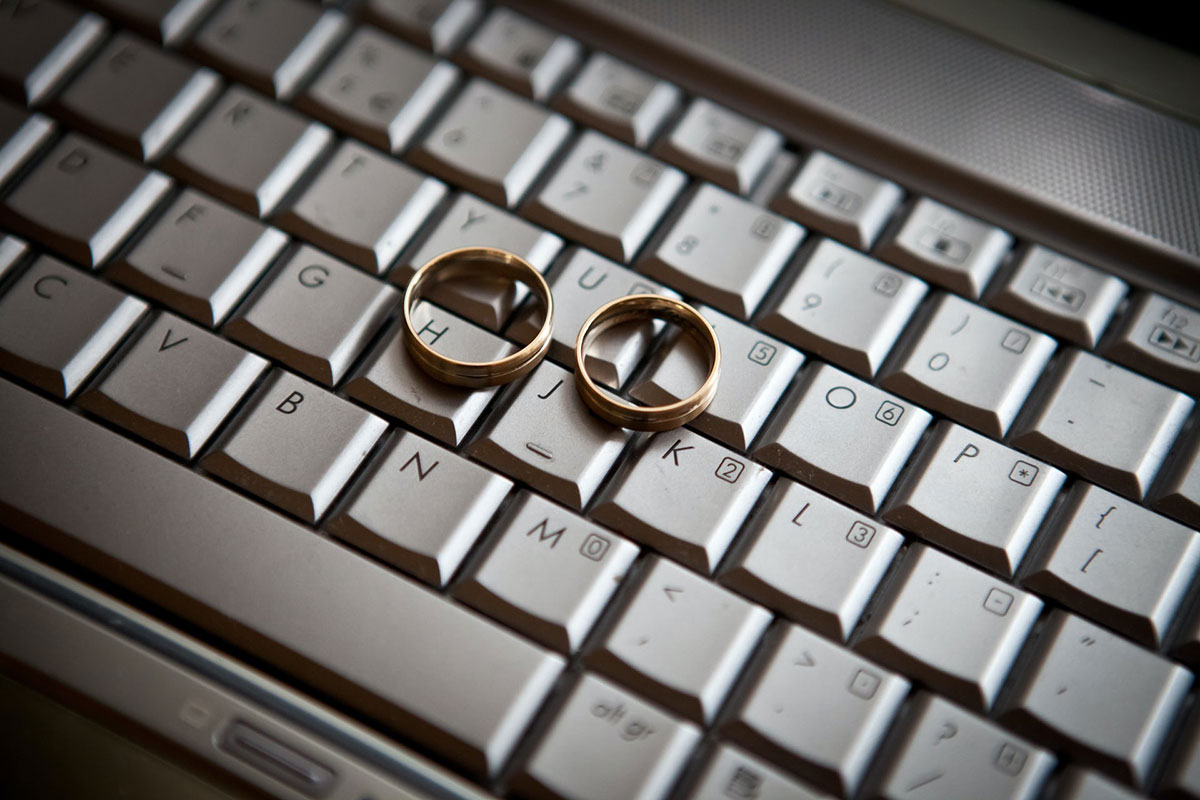 A pair of wedding rings sit on a laptop keyboard