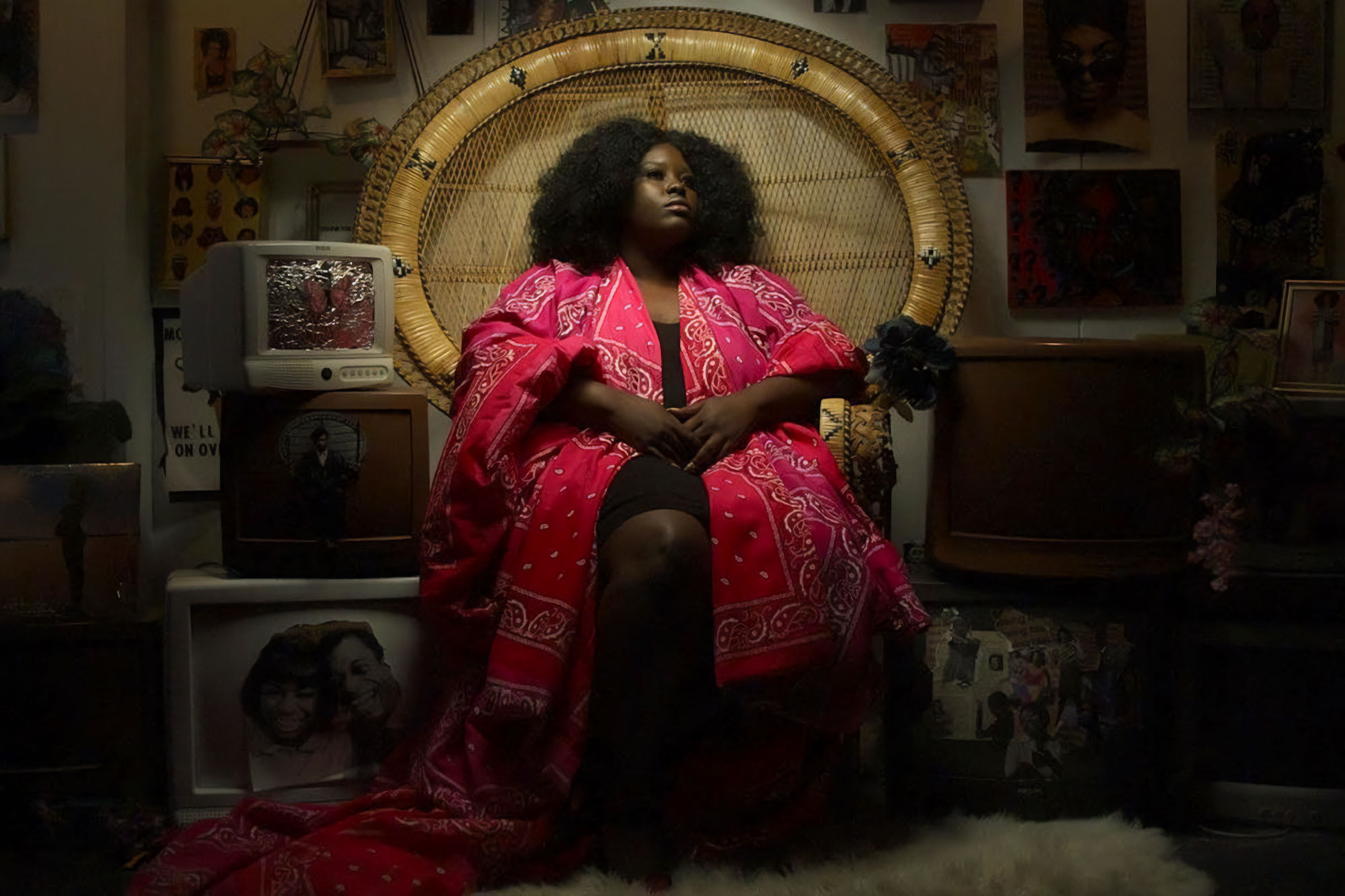 A woman in a long pink robe sits in a throne like chair