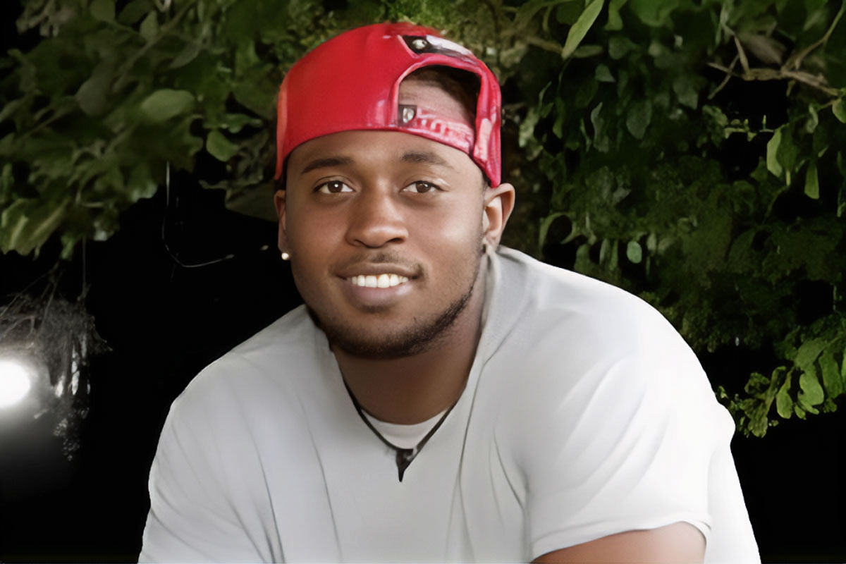 Damien Cameron in a white tshirt and red hat