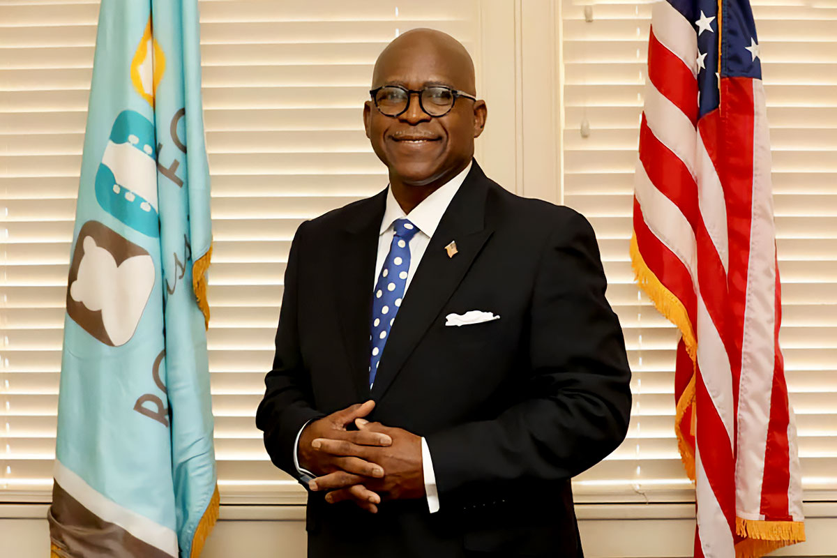 Official photo of Mayor Eldridge Walker standing inside between two flags