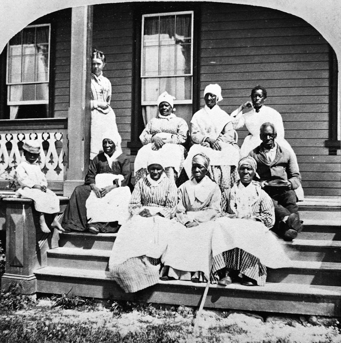 A group of enslaved African women and a man sit on the steps of a porch. (Enslaved Africans)