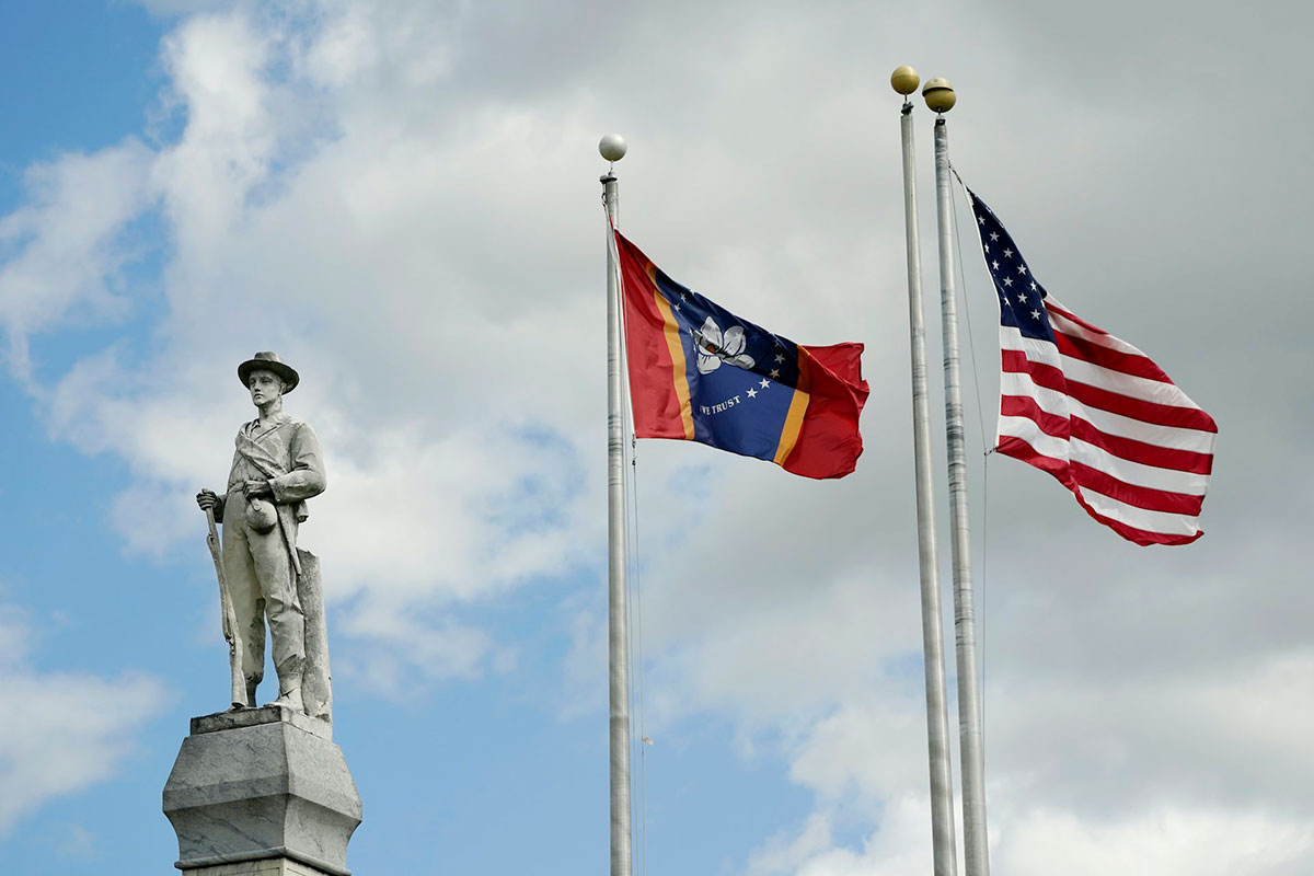 Two flags fly near a monument to a soldier