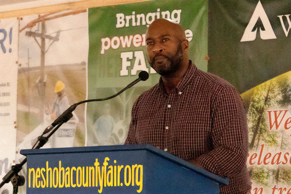 Shuwaski Young speaking at a blue podium labeled Neshoba County Fair
