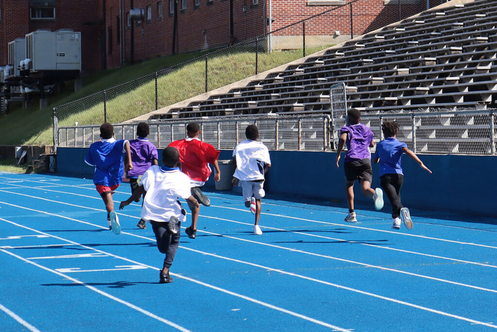 Several children running away along a blue race track