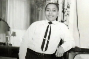 Emmett Till leaning against a piece of home furniture