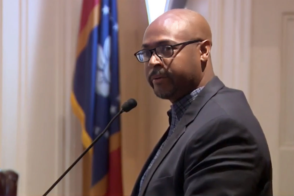 Profile of Khalid Woods speaking at a podium