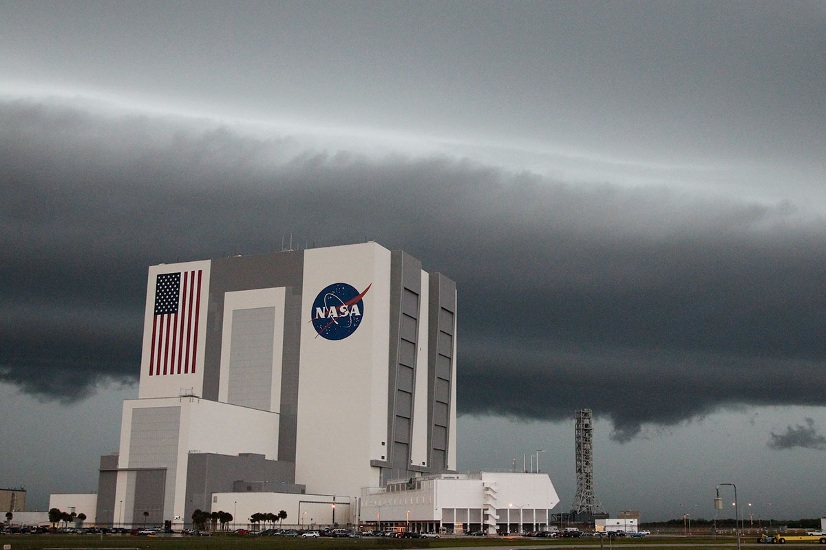 A view of a NASA building from the distance with dark storm clouds behind it