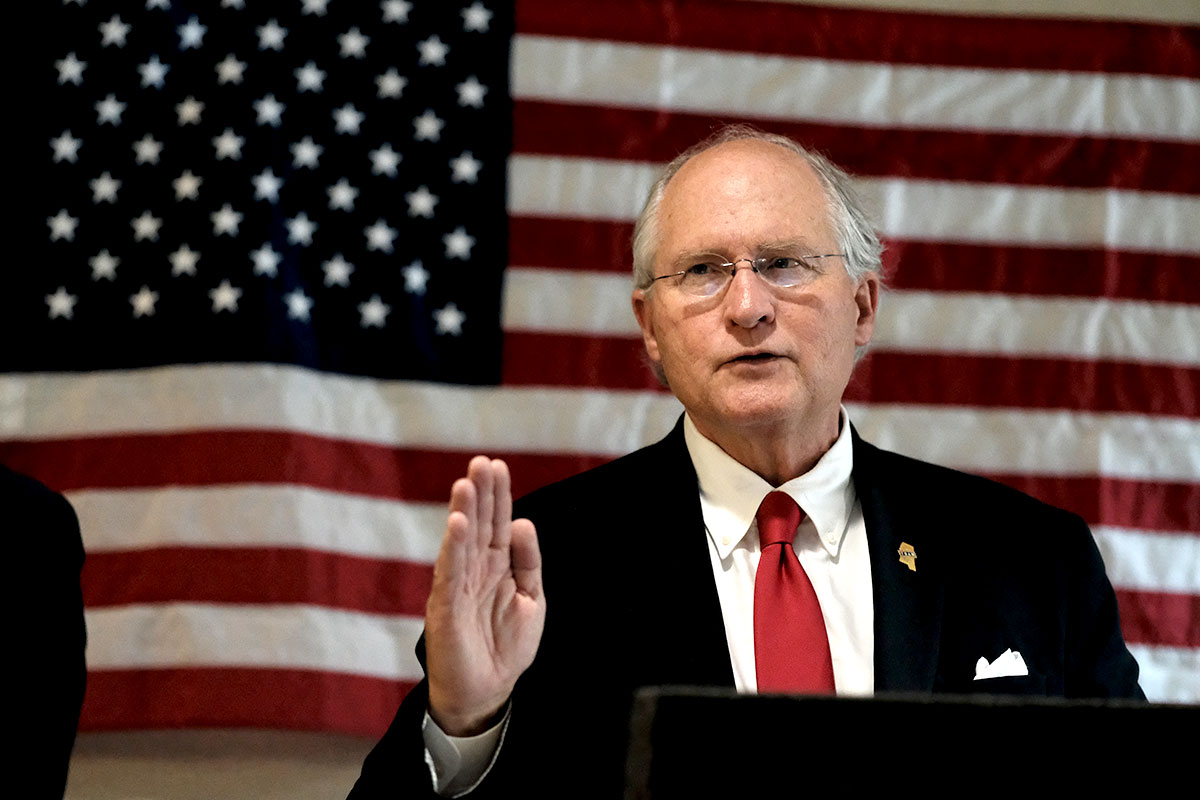 William Waller speaking at a podium before a US Flag